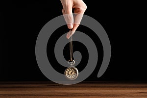 Psychotherapist with pendulum on black background, closeup. Hypnotherapy session