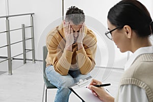 Psychotherapist working with drug addicted man indoors