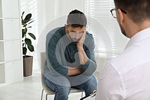 Psychotherapist working with drug addicted man indoors