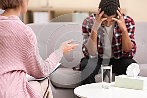 Psychotherapist working with teenage African-American boy in office