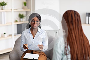 Psychotherapy consultation. Counselor talking to black woman on meeting at office, giving advice to young client photo