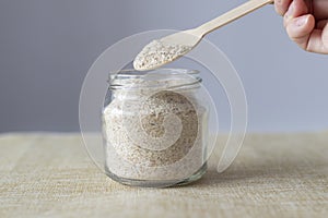 Psyllium. Plantain husk in a wooden spoon and jar, a prebiotic superfood fiber food for intestinal health