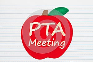 PTA meeting message on a wooden apple on vintage ruled line notebook paper photo