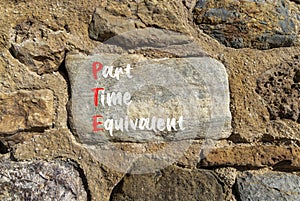 PTE Part time equivalent symbol. Concept words PTE Part time equivalent on beautiful big stone in stone wall. Beautiful stone wall