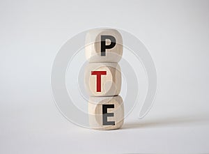 PTE - Pearson Tests of English symbol. Wooden cubes with word PTE. Beautiful white background. Business and PTE concept. Copy