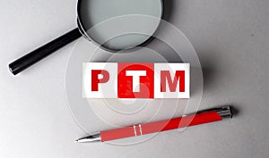 PTM word on wooden cubes with pen and magnifier