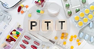 PTT - Partial Thromboplastin Time, word on wooden blocks on a desk. Medical concept with pills, vitamins, stethoscope and syringe