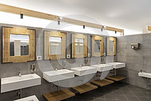 Public bathroom with five sinks, mirrors and soap dispensers. Modern and simple