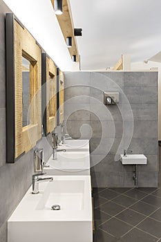 Public bathroom with five sinks, mirrors and soap dispensers. Modern and simple