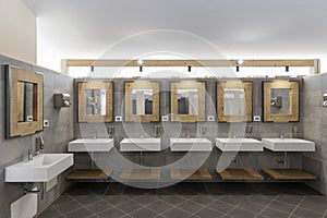 Public bathroom with five sinks, mirrors and soap dispensers. Modern and simple