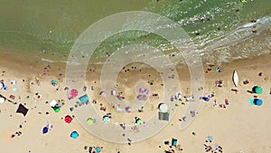 Public beach in mid summer with colourful umbrellas, people in the water and on the beach.