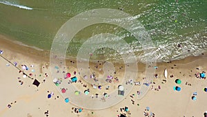 Public beach in mid summer with colourful umbrellas, people in the water and on the beach.