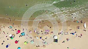 Public beach in mid summer with colourful umbrellas, people in the water and on the beach.