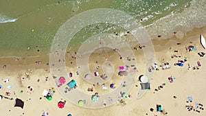 Public beach in mid summer with colourful umbrellas, people in the water and on the beach.