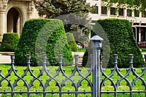 public city park in Budapest with decorative old gray cast iron railing. low picket fence. lush green lawn