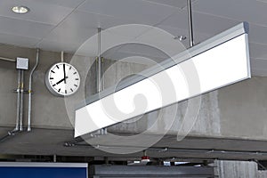 Public clock and blank sign board for information in railway station at the hanging with roof of subway central train station. It