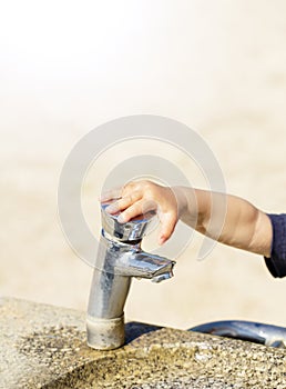 Public drinking fountain with childâ€™s little hand in city park