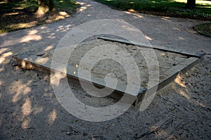 Public multifunctional playground with a sandy impact zone and a stainless steel slide in the park with a sandpit, a climbing