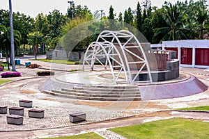 Public outdoor performance stage with arch metal roof background. Amphitheater with circle platform at public Royal Park