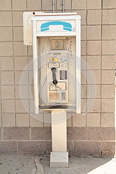 public pay phone outside outdoors against building wall, portrait. p