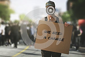 public protest and riots in the city streets. woman with megaphon and cardboard poster in hands on protesters crowd background