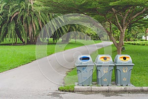 Public recycle bins or segregated waste bins sitting on concrete floor beside walkway in public park. photo