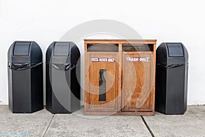 Public Recycling Station With Separate Bins for Pizza Boxes and Trash Against a Wall