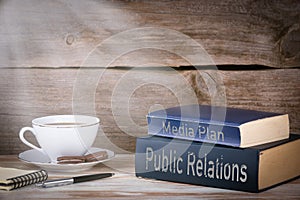 Public Relations and Media Plan. Stack of books on wooden desk