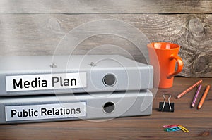 Public Relations and Media Plan - two folders on wooden office desk photo