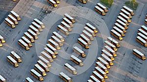 Public school bus parking lot with many yellow buses parked in rows. American education system transportation