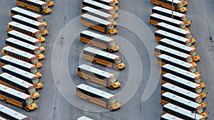 Public school bus parking lot with many yellow buses parked in rows. American education system transportation