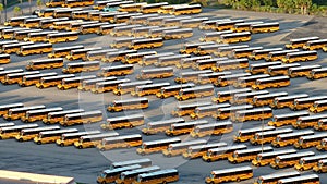 Public school bus parking lot with many yellow buses parked in rows. American education system transportation