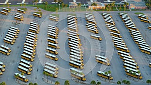 Public school bus parking lot with many yellow buses parked in rows. American education system transportation