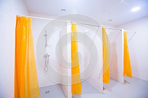 Public shower room with several showers. Big, light, empty public shower room, with bright walls and gray floor