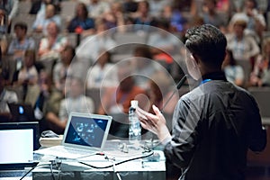 Public speaker giving talk at Business Event.