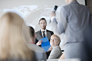 Public speaker looking at businesswoman answering during seminar