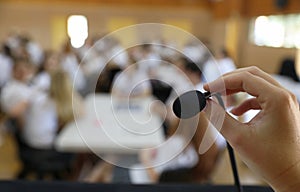 Public speaking fear. Person about to speak into a small microphone in front of a large crowd photo