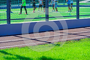 Public stadium for sports - team of soccer players on a football field, running track closeup and green grass