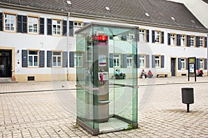 Public telephone on pathway beside traffic road in small alley at Speyer town