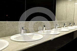Public toilet and bathroom interior with wash basin..Faucets with of washbasins in public toilet room..Modern sinks with mirror
