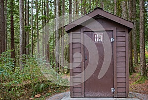 Public toilet in park. Summer day Wooden restroom or toilet building in remote forest in park. Bathrooms or WC photo