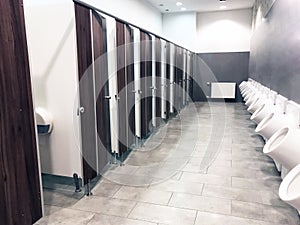 Public toilet restroom with doors and urinals in a row