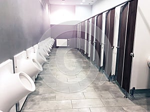 Public toilet restroom with doors and urinals in a row
