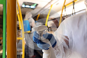 Public transport sanitation. Worker in protective suit disinfecting bus salon, closeup