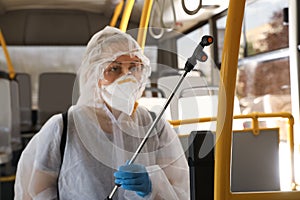 Public transport sanitation. Worker in suit disinfecting bus salon, focus on spray machine nozzle