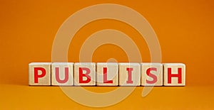 Publish symbol. The concept word Publish on wooden cubes. Beautiful orange table, orange background, copy space. Business publish