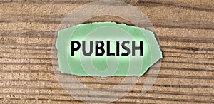 PUBLISH - word on green torn piece of paper on old brown board background
