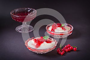 Pudding from semolina in a glass bowl with red currant syrup and berries. On a dark background