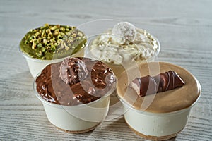 Puddings in four cups covered with creams having different tastes