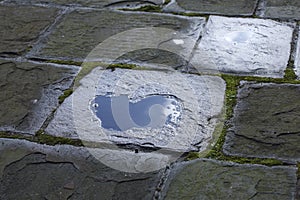 Puddle forming a heart on a stone tile